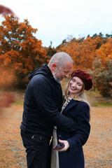 Fototapeta premium Happy pair embracing autumn vibes, sharing laughter as he lifts her for a selfie
