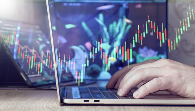 hands typing on laptop with green and red candlestick chart overlay, symbolizing rising market trends and investments. - Powered by Adobe