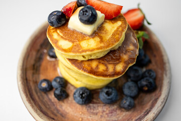Top View Stack of Pancakes with Butter, Strawberries and Blueberries on Plate