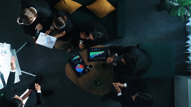 Top down view of business people listen businessman present idea while making decision. Group of diverse team making a decision to invest start up project while hold tablet display graph. Directorate.