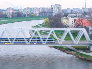 pociąg osobowy jedzie szybko przez most nad rzeką © Henryk Niestrój