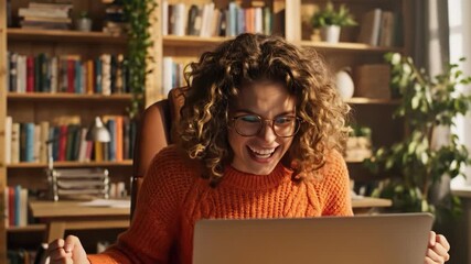 Excited woman celebrating success with arms raised in front of laptop