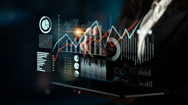 A businesswoman uses a digital interface to analyze financial data and trends in a modern office setting, showcasing advanced technology in analytics and professional insight. Scalp