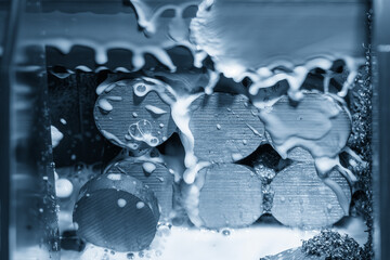 Close up scene the band saw machine cutting the metal shaft parts with coolant method in the light...