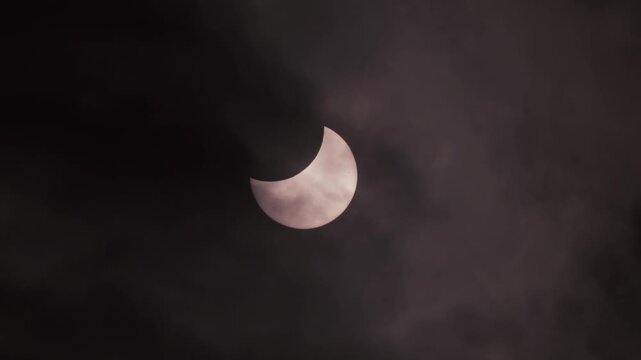 Solar Eclipse with Dramatic Dark Clouds Moving Across Partially Eclipsed Sun