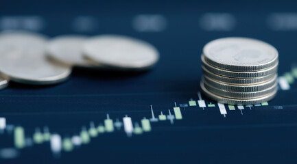  Silver coins stacked on financial trading chart represent investment growth analysis.
