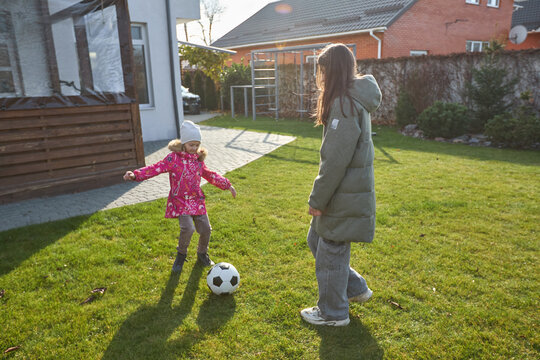 Children playing soccer in suburban backyard on a sunny day