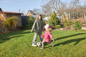 Sisters playing soccer in autumn garden