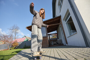 Woman balancing on skateboard in residential backyard on sunny day