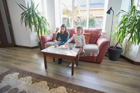 Cozy living room with kids enjoying a snack on a red sofa - Powered by Adobe