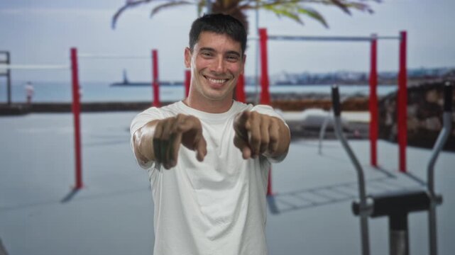 Man smiling and pointing finger at camera next to red parallel bars in gymnasium; confidence motivation.