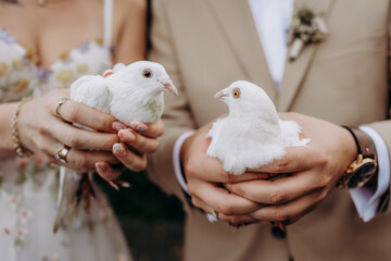 Para młoda trzyma w dłoniach dwa gołębie