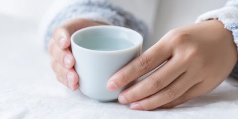 Hands holding a white cup with water concept of refreshment and hydration