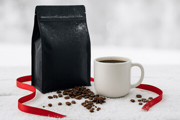 Warm coffee cup beside black coffee bag and spilled beans on a snowy surface