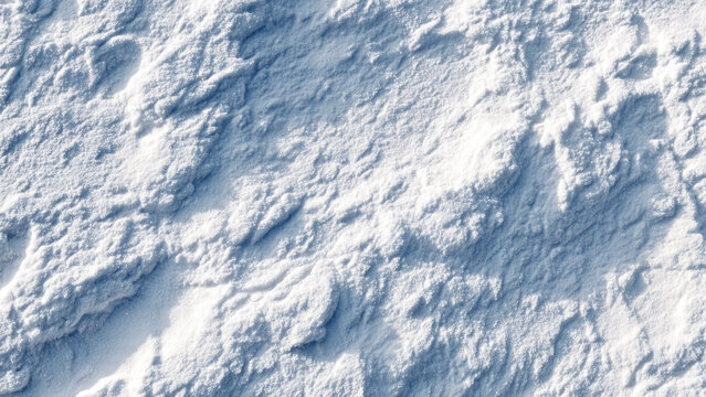 Close-up aerial view of textured snow or fine white powder, showing uneven contours, granular details, and subtle blue shadows.