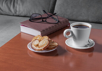 Coffee, pastries and book in cozy indoor scene.