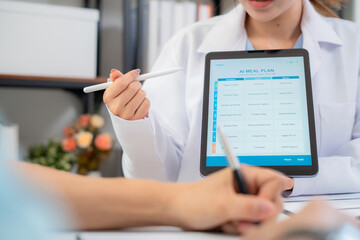 Close up nutritionist using tablet to explaining personalized meal plan with AI to patient during healthcare consultation, healthy lifestyle, woman dietitian showing nutrition plan with AI on tablet.