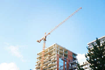 A tall crane is building a tall skyscraper to the very clouds