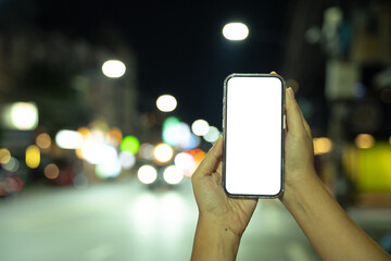 Woman hand holding empty screen of smartphone with bokeh at night time