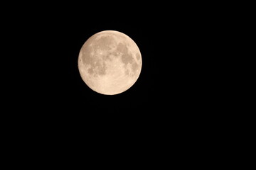 A bright, detailed full moon with a warm yellow glow, isolated on a pure black night sky. This...