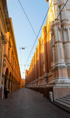 Sunlit Medieval Street and Basilica Facade in Bologna, Italy