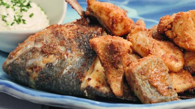 Fried fish dorado in batter with tartar sauce and lemon slices. High quality 4k footage