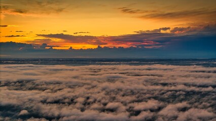A high-altitude aerial photograph capturing a sunrise above a vast forest with golden morning mist drifting through the treetops