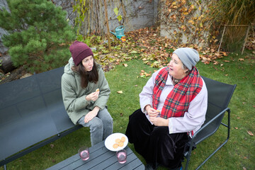 Two women having a casual chat outdoors in autumn attire
