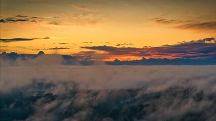 A high-altitude aerial photograph capturing a sunrise above a vast forest with golden morning mist drifting through the treetops