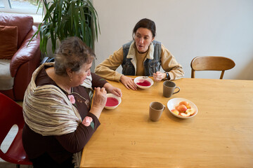 Two women sharing a meal and conversation at a wooden dining table