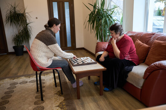 Two women playing checkers in cozy living room setting