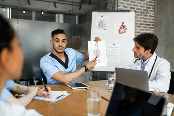 Middle eastern man doctor having speech while medical conference, showing picture with human body...