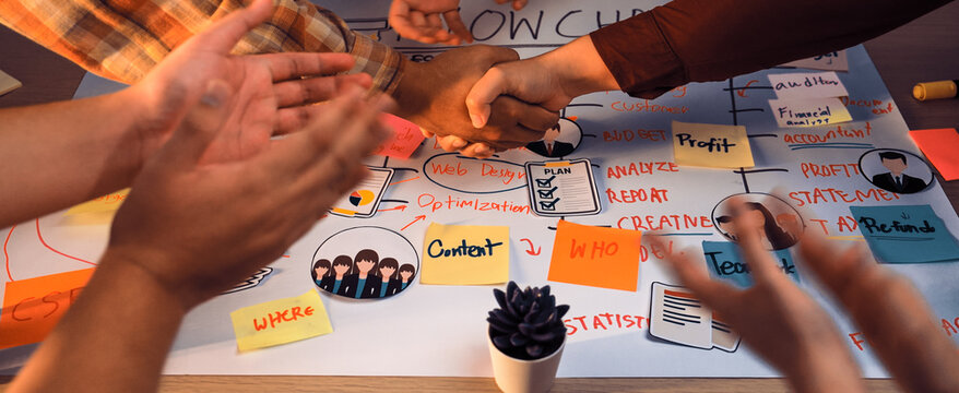 Diverse hands come together in a collaborative meeting, shaking hands over an insightful flowchart, highlighting teamwork and creativity among engaged participants. SACTR