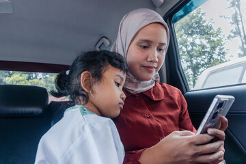 An Asian Muslim mother showing something to her daughter in smartphone