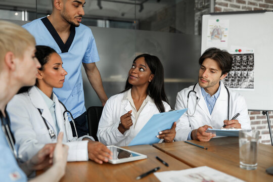 International medical staff men and women having team-building at hospital, listening to head chief physician middle eastern man, discussing various medical cases, planning working day