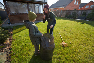 Mother and child cleaning the backyard together on a sunny day