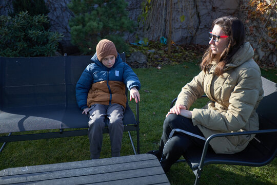 Mother and child relaxing outdoors in winter coats on a sunny day - Powered by Adobe