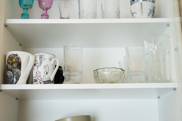 Shelf with assorted glassware and mugs, creating a bright, organized kitchen cupboard scene.