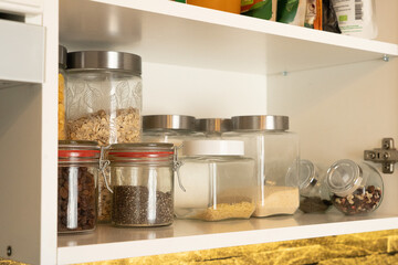 Neat pantry cabinet with glass jars of grains and seeds, adding warmth and order to a home kitchen.