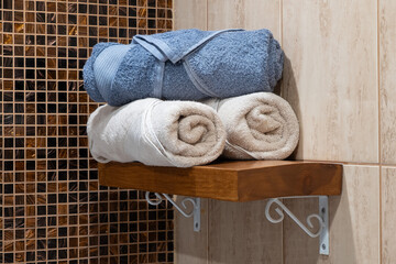 Fresh bathroom scene with blue and white towels neatly folded on a wooden shelf, creating a clean and serene mood.