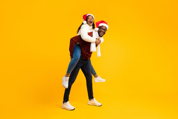 An African American couple is having fun during Christmas, with the husband giving his wife a...