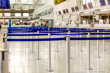 Metallic barrier poles with blue retractable belts in a row located in an airport terminal