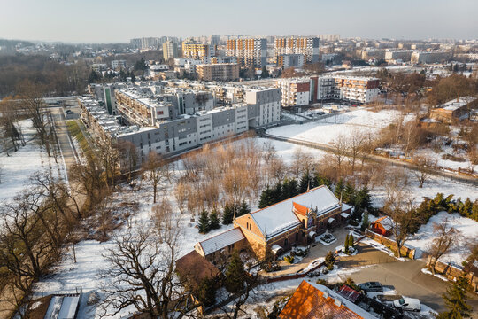 Aerial view of the historic Jerzmanowski Manor (Pałac Jerzmanowskich) and surrounding park in Krakow, Poland, contrasted with modern residential estates in winter.
