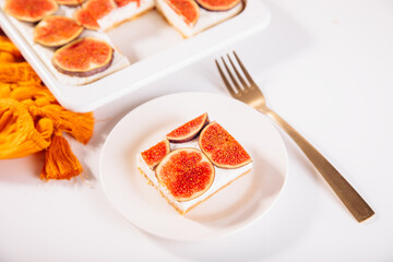 A delicious slice of fig and cream cheesecake on a white plate, topped with fresh fig slices