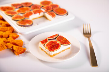 A delicious slice of fig and cream cheesecake on a white plate, topped with fresh fig slices
