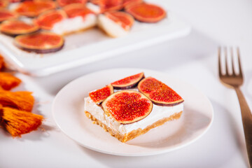 A delicious slice of fig and cream cheesecake on a white plate, topped with fresh fig slices