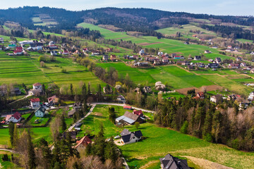 Aerial drone view of Ratułów (Rokociny Podhalańskie) village in the Podhale region, Poland. Scenic summer landscape featuring rolling hills and traditional rural houses.
