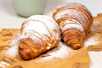 Detailed macro shot focusing on the flaky texture and powdered sugar of a fresh croissant.