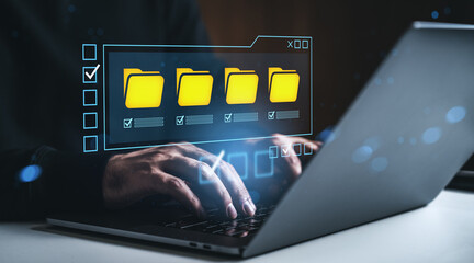 Businessman managing digital file folders on laptop with futuristic interface in modern workspace concept, creative digital data organization scene.