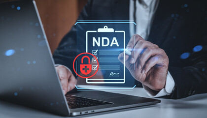 Businessman signing digital NDA agreement on laptop with cybersecurity lock icon, emphasizing data confidentiality and privacy concept background.
